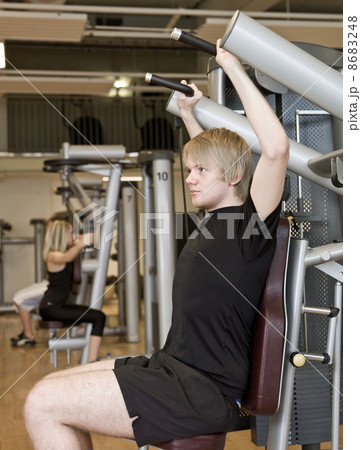 Young man using an exercise machine Young man using an exercise machine 8683248