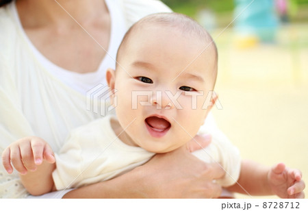 公園でママに抱っこされている笑顔の赤ちゃん 8728712