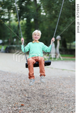 Happy teenager boy having fun swinging on playground 8754094