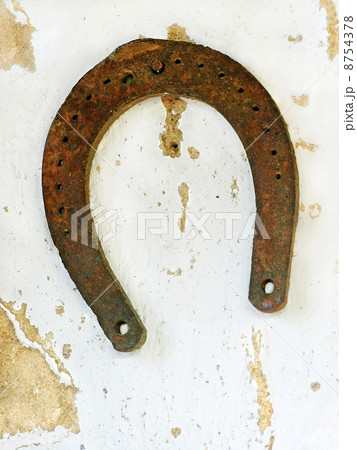 Old lucky horseshoe on aged white clay wall background. 8754378