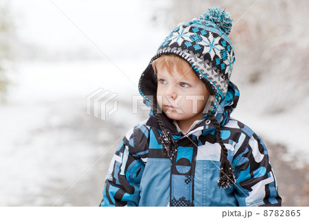 Adorable toddler boy having fun with snow on winter day 8782865
