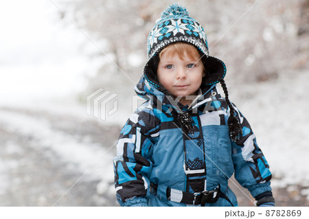 Adorable toddler boy having fun with snow on winter day 8782869
