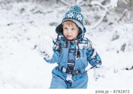 Adorable toddler boy having fun with snow on winter day 8782872