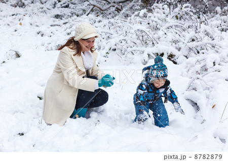 Mother and toddler boy having fun with snow on winter day 8782879