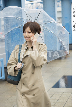 傘をさしながら携帯で話す女性 8789438