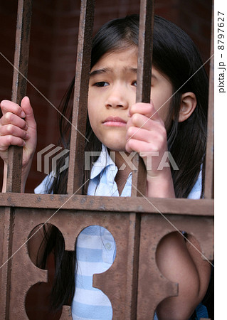 Little girl standing behind iron bars Little girl standing behind iron bars 8797627