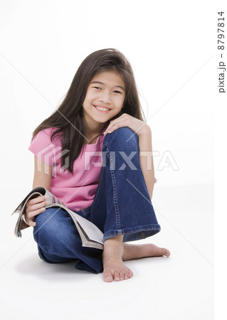 Little girl sitting on floor reading a magazine 8797814
