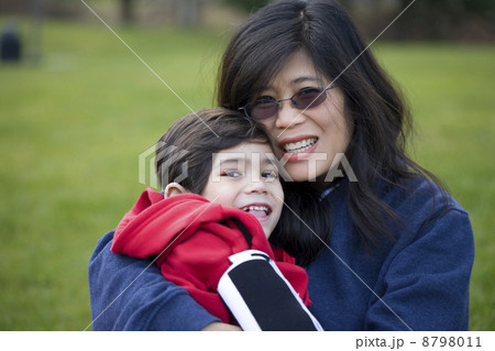 Beautiful asian mother holding her disabled son at park 8798011