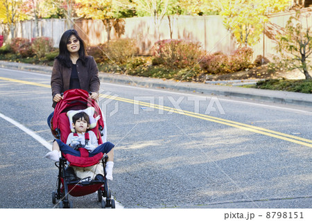 Mother pushing her son in the stroller 8798151