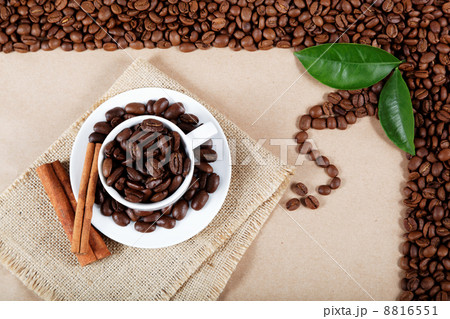 Cup with coffee beans and cinnamon sticks on sackcloth. Cup with coffee beans and cinnamon sticks on sackcloth. 8816551