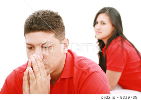 Young sad man sitting on bed, nearby unsatisfied woman. Young sad man sitting on bed, nearby unsatisfied woman. 8839789