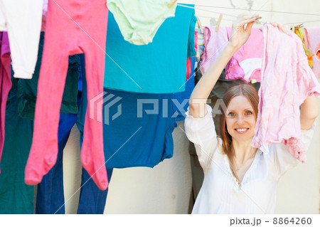 Positive girl drying clothes on clothes-line Positive girl drying clothes on clothes-line 8864260