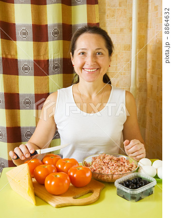 woman with ingredients for stuffed tomato 8864632
