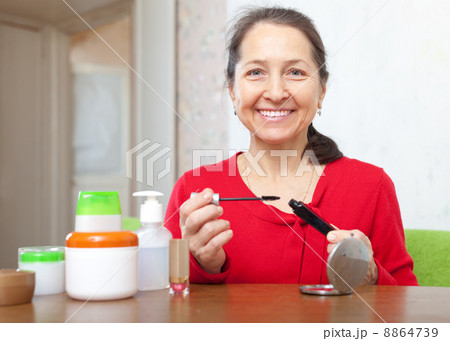 mature woman puts mascara on 8864739