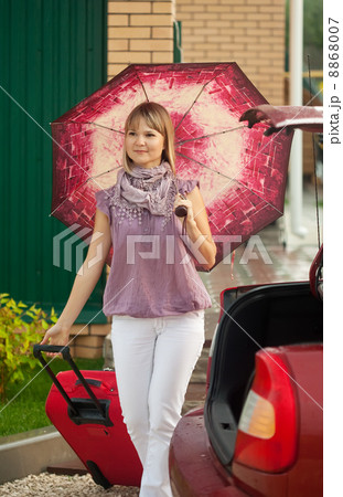 woman with luggage walking to car 8868007