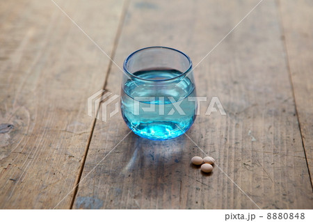 飲み薬と青ガラスのコップに入った水 8880848