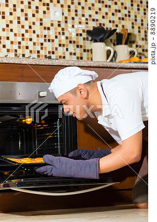 Asian man baking cake in home kitchen 8890219