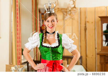 Young woman as queen in Traditional Bavarian Tracht in restaurant 8890230