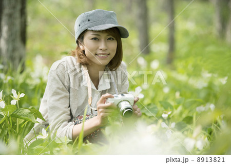 ミラーレス一眼カメラを持ち微笑む女性 8913821
