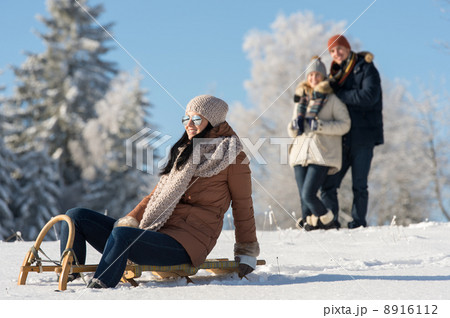 Friends enjoy sunny winter day on sledge 8916112
