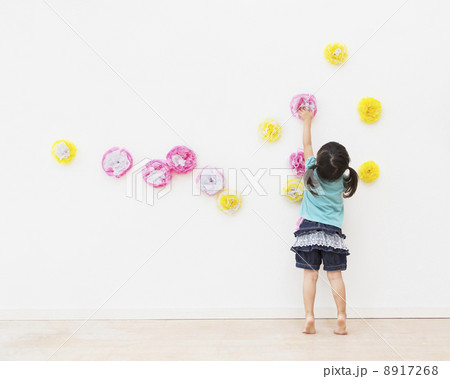 壁に花の飾りを飾る女の子 8917268