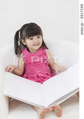 ソファに座ってアルバムを開ける女の子 8917288