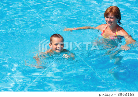 Mother train her son to swim in the pool. 8963168