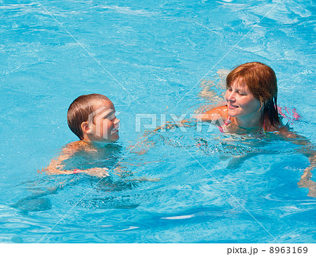 Mother train her son to swim in the pool. 8963169