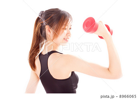 腕の筋肉を見ながらトレーニングをするポニーテールの若い女性の写真素材