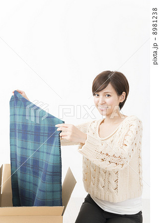 衣類を手にする女性とダンボール箱 8981238