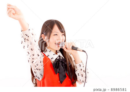 片手を高く振り上げてノリノリでカラオケを楽しむ可愛らしい女の子の写真素材