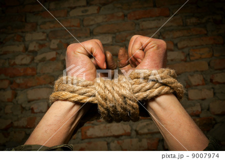 Hands of man tied up with rope 9007974