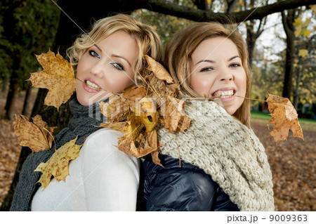 Two beautiful women with dry leaves in the teeth by autumn. Two beautiful women with dry leaves in the teeth by autumn. 9009363