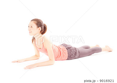 床に寝そべりヨガのコブラのポーズをする若い女性の写真素材