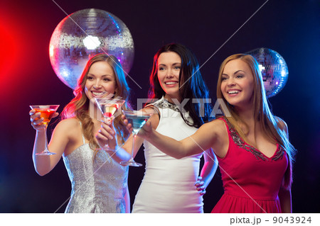 three smiling women with cocktails and disco ball 9043924