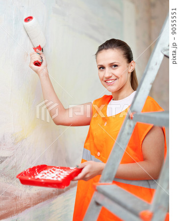 painter paints wall with roller 9055551