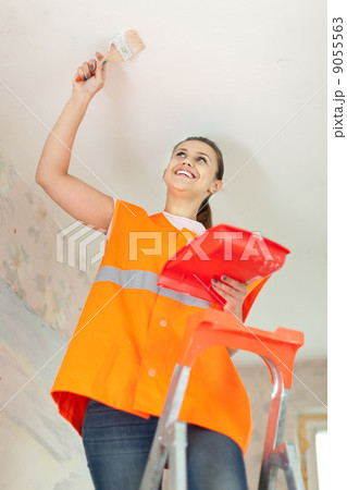 Female house painter paints the ceiling 9055563