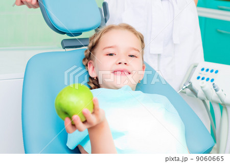 girl in the dentist's chair shows a green apple 9060665