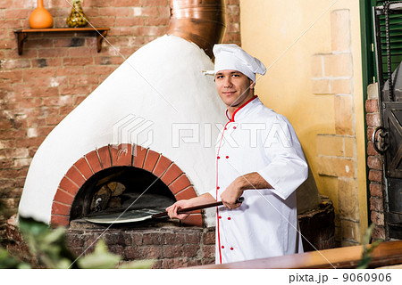 Chef puts dough in the oven for pizzas, 9060906