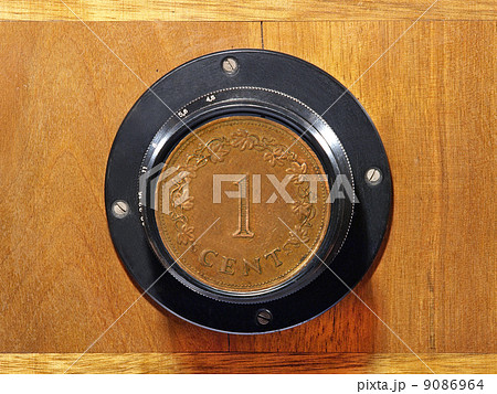 Old camera lens with one cent coin inside. 9086964