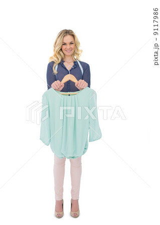 Happy blonde fashion designer holding blouse 9117986
