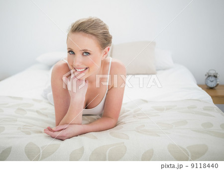 Natural smiling blonde lying on bed 9118440