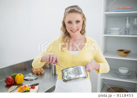 Happy cute blonde stirring with wooden spoon 9118455