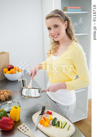 Smiling cute blonde stirring with wooden spoon 9118716