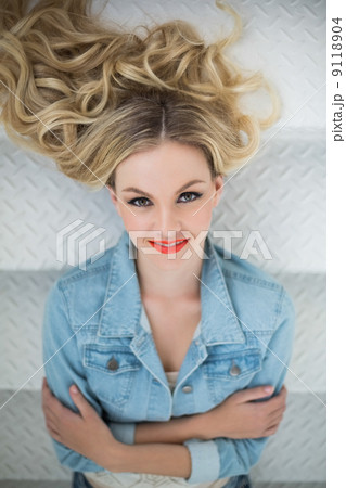 Smiling blonde wearing denim clothes lying on stairs Smiling blonde wearing denim clothes lying on stairs 9118904