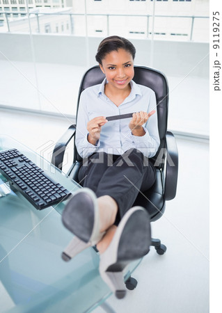 Cheerful young dark haired businesswoman filing her nails while 9119275