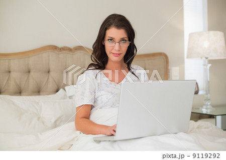 Stern pretty brown haired woman typing on a laptop Stern pretty brown haired woman typing on a laptop 9119292