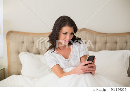 Concentrated pretty brown haired woman typing on a mobile phone 9119305