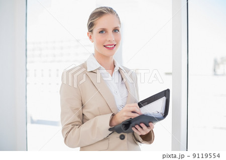 Smiling blonde businesswoman writing on datebook Smiling blonde businesswoman writing on datebook 9119554