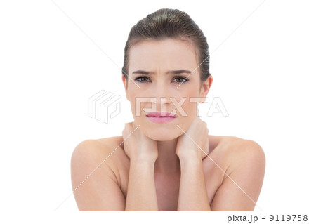 Frowning natural brown haired model holding her neck 9119758